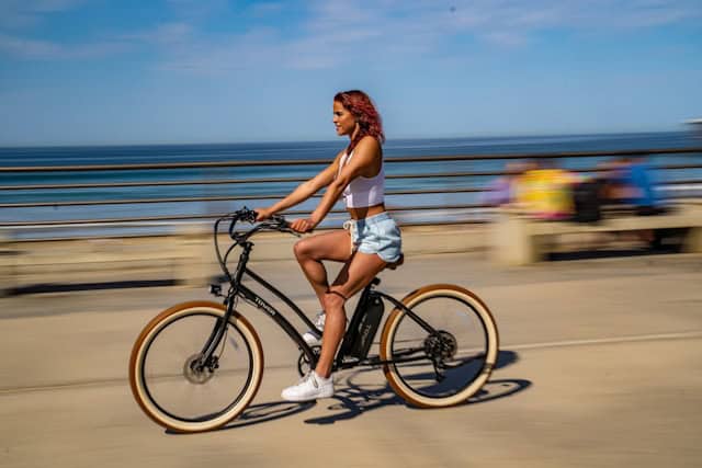 A girl on a cruiser bike on Amelia Island, with the Atlantic Ocean shimmering behind and tire tracks trailing through soft white sand.