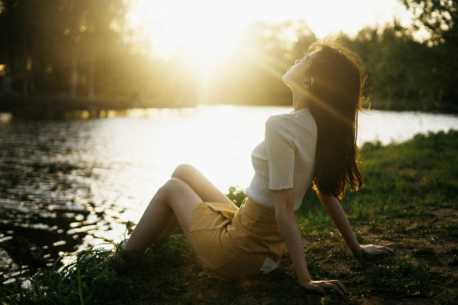 woman in white shirt and brown shorts sitting on brown wooden log during daytime