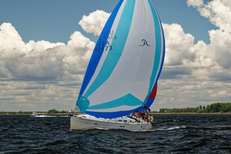 a sailboat with blue and white sails on a body of water